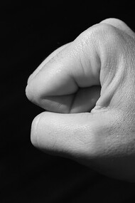 A grayscale image of a clenched fist against a black background