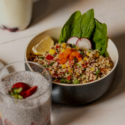 Sliced fruits, quinoa, and fresh vegetables served in a black ceramic bowl as a wholesome low-calorie meal