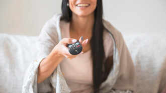 Engaged in the experience, the woman watches live-streamed content, reflecting the increasing appeal of interactive and real-time events on platforms like YouTube and Twitch