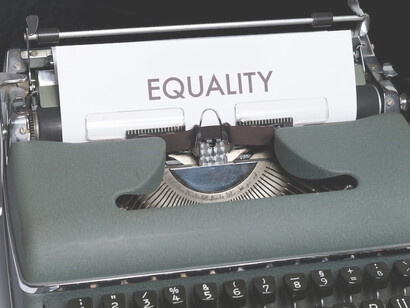 A typewriter sits with a sheet of paper reading "equality"