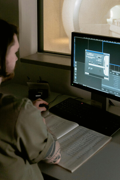 A medical technician monitors detailed brain scans in real time during an MRI procedure.