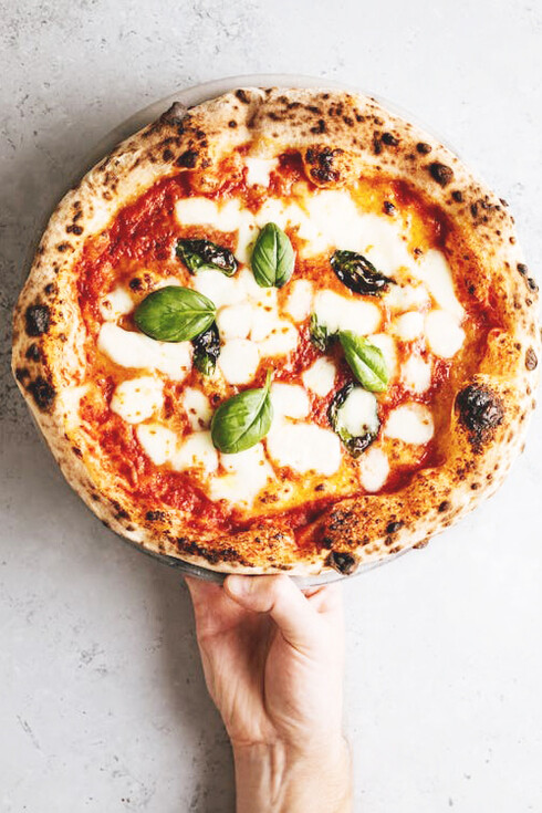 A hand holding a slice of pizza in Rome, Italy