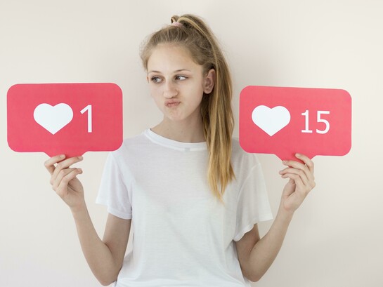 A girl posing with digital “like” symbols, illustrating online validation