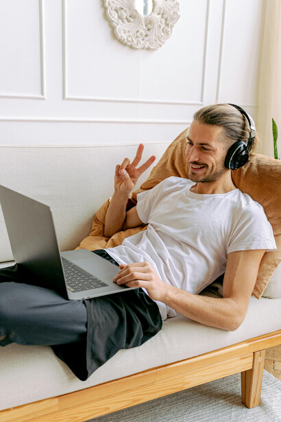 A man on a video call forms a heart shape with his hands, showing love in a long-distance connection