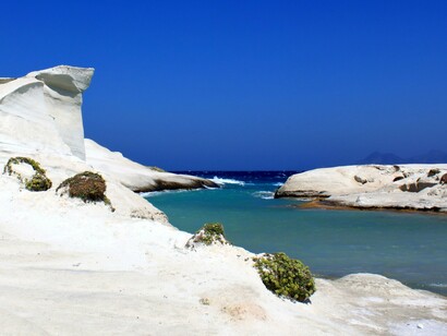 Sculpted volcanic formations rising above crystal-clear waters, reflecting the rugged landscape that draws travelers to Milos