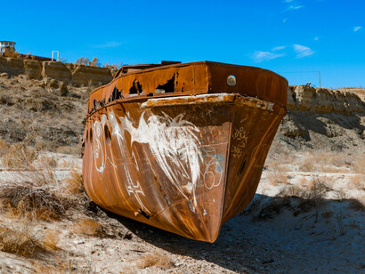 In Muynaq, Uzbekistan, an abandoned rusty ship lies stranded on the sands of the former Aral Sea, symbolizing ecological collapse, drought, and environmental change