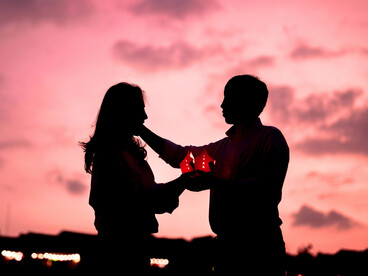 A warm lantern glowing softly in the hands of a couple, symbolising love that survives through hardship and longing