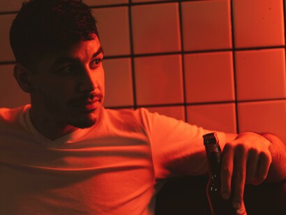 A man in a white t-shirt drinking from a bottle 