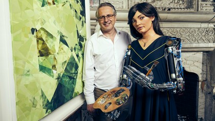 Ai-Da com o galerista Aidan Meller no Reino Unido, 2019. Há décadas, artistas programam algoritmos para criar imagens, sons e textos. Mas então, o que torna a obra de Ai-Da uma novidade?  A novidade não está no seu processo criativo, mas no espetáculo cuidadosamente construído ao seu redor