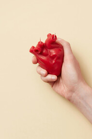 A red heart held tightly on one hand