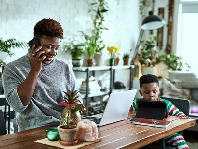 A woman working remotely while also keeping an eye on her son