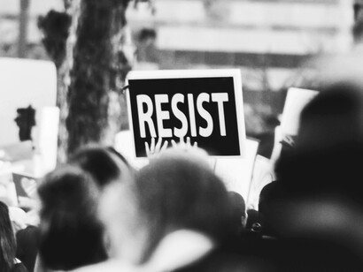 Monochrome image of a protest placard displaying ‘Resist’
