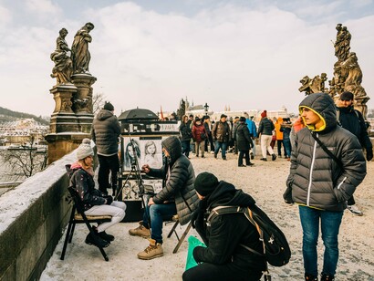 A street artist creating portraits amid the bustle of Charles Bridge, Prague, representing the city’s vibrant artistic spirit