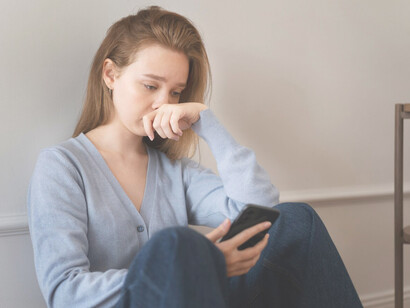 Anxious woman holding a smartphone, feeling stressed or overwhelmed