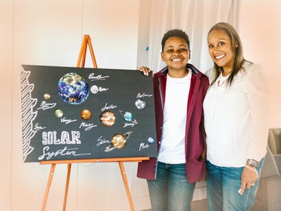 Estudante posa orgulhoso ao lado de sua montagem do sistema solar. Mapas conceituais são representações visuais que ajudam os alunos a compreender as relações entre conceitos e como os novos conhecimentos se conectam ao que já foi aprendido. Essa ferramenta facilita a organização mental das ideias, auxiliando na retenção e na compreensão profunda
