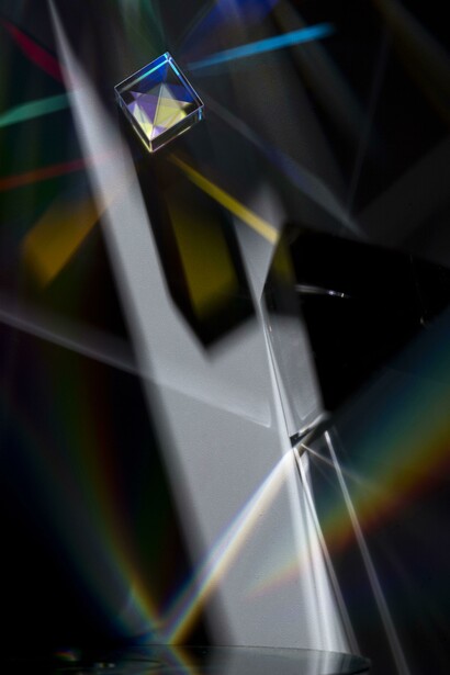 Un prisma verticale disperde la luce in un vivido arcobaleno su sfondo nero