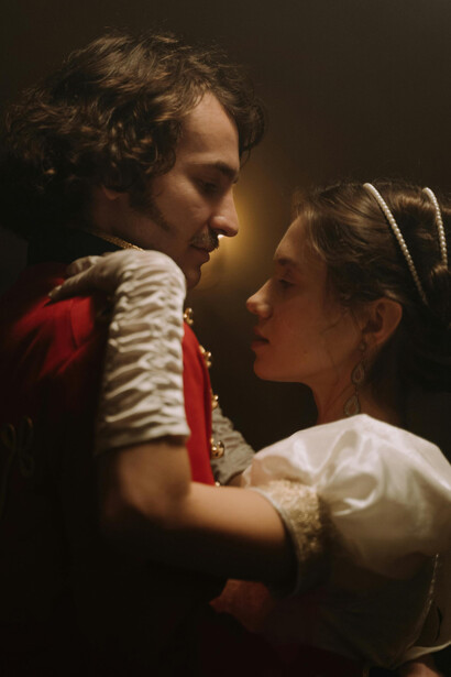 A couple dancing in candlelight, dressed in elegant 18th-century aristocratic fashion