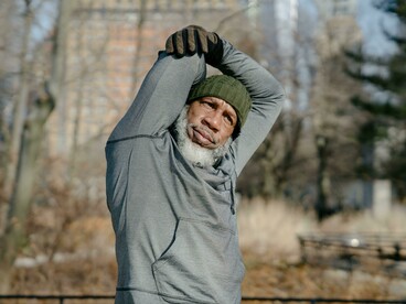A senior Black male exercising outdoors in a fall setting, maintaining strength and well-being