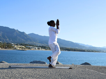 A yoga practitioner doing a pose beside the sea, representing inner balance amidst life’s changing situations