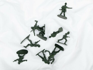 Scattered toy soldiers lying across a white surface, representing the lasting human cost of war and the memories that continue to shape Germany's policies