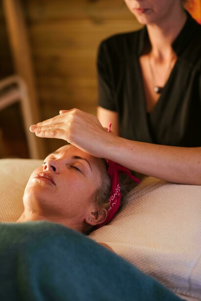 In a moment of stillness, reiki hands hover gently, guiding the woman into a state of peace and energetic renewal