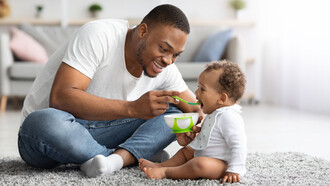 Un hombre alimenta a su pequeño hijo