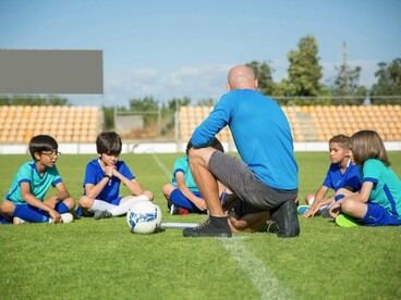 A coach sharing a moment with his team, symbolising how sport can nurture confidence rather than ranking ability