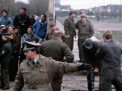 An East German policeman gestures to the crowd as people gather on the West German side during the dismantling of the Berlin Wall at Potsdamer Platz