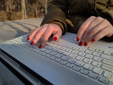 Focused and deliberate, a person types on their laptop keyboard while working