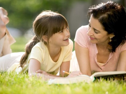 Una madre habla con su hija mientras leen un libro