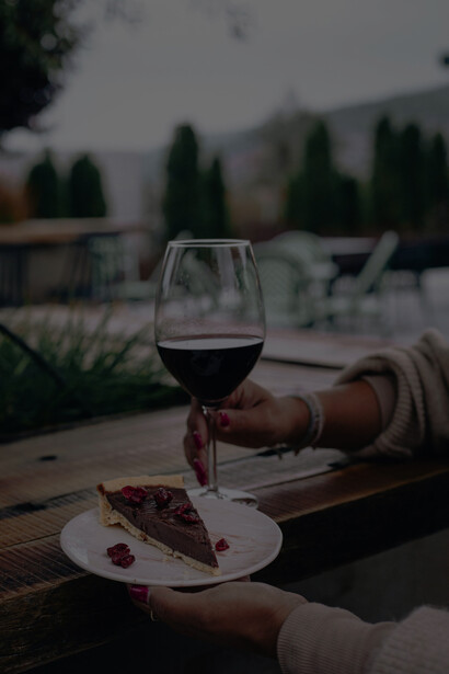 At the table, a woman enjoys cakes alongside a variety of wines, creating a delightful pairing experience