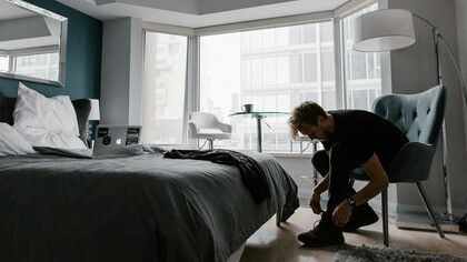 Homem acorda cedo na jornada da contemplação, amarrando os sapatos para encarar a rotina