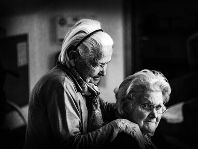 Two elderly female friends, help one another