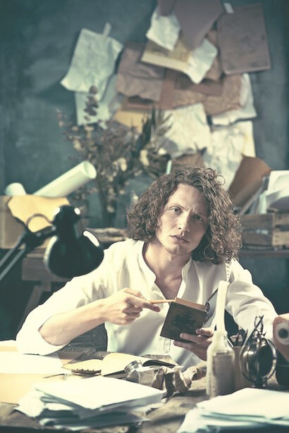 A young philosopher, seated at a table, earnestly recording thoughts in his sketchpad