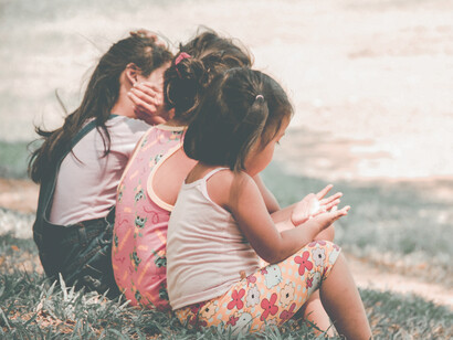 Tres niñas sentadas en el cesped de un parque de la ciudad Quezon en Filipinas
