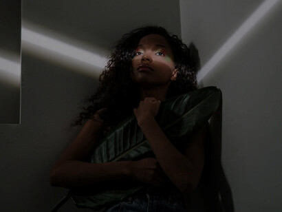 With grace, a woman holds a colossal leaf in her hand