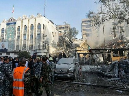 Equipes de segurança e emergência trabalham entre veículos e estruturas destruídas diante do consulado iraniano em Damasco. A dimensão dos danos expõe a vulnerabilidade de uma região onde instalações diplomáticas, forças militares e interesses estratégicos passaram a estar cada vez mais próximos do campo de batalha