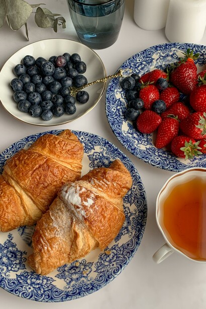 Croissants next to a bowl of blueberries and strawberries