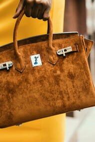 Woman carrying a brown Hermès leather tote, blending elegance with timeless design