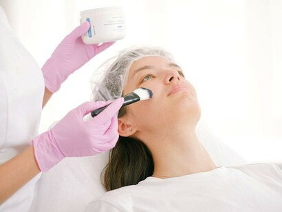 A woman undergoing a cosmetic procedure at a clinic, assisted by a doctor