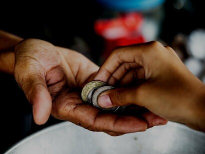 Una mano porge delle monete a un’altra, rappresentando un semplice gesto di pagamento o aiuto economico