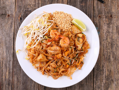 Delicious Pad Thai noodles are presented on a rustic wooden background
