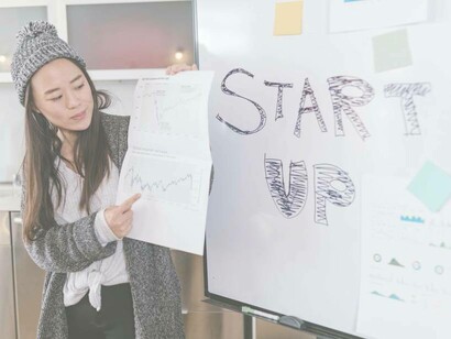 A young businesswoman holding up a sheet of information related to her startup as she pitches to investors