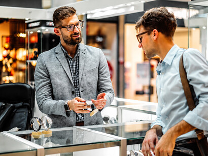 Watch dealer carefully presenting a timepiece to a customer in a shopping mall