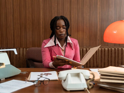 A professional African woman reviewing documents at her desk, representing the growing opportunities that allow women to pursue ambitious careers