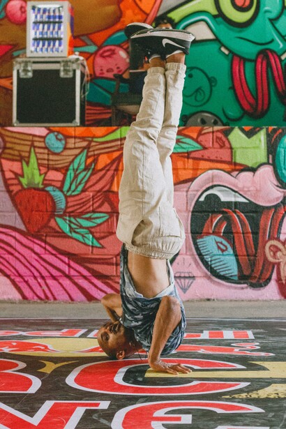 Man doing a head stand in front of a graffiti wall