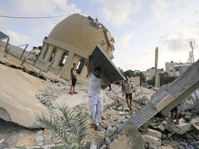 Personas intenta rescatar materiales de  la mezquita destruida en en Khan Younis, Franja de Gaza