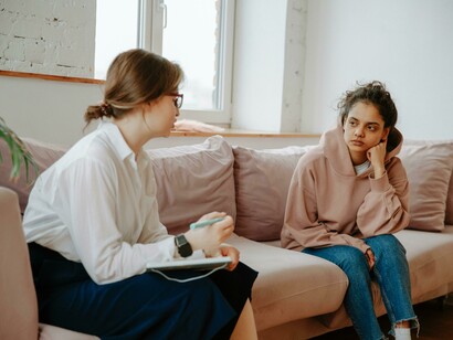 A young woman talking with a therapist, symbolizing teenage mental health and the struggles of overwhelmed or stressed teen girls
