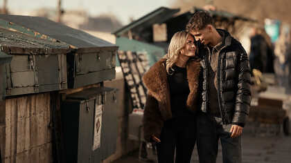 Young couple enjoying a romantic walk beside a dumpster in a gritty urban alley