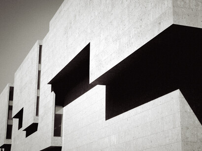 Composición geométrica en blanco y negro de un edificio moderno con volúmenes angulares de hormigón y marcados contrastes de sombras
